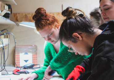 Trois personnes bricolant sur l'établi du FabLab